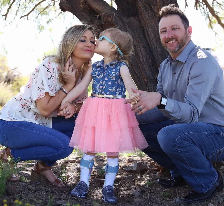 A family is posing for a picture with a little girl who has cerebral palsy. A family is posing for a picture with a little girl who has cerebral palsy.
