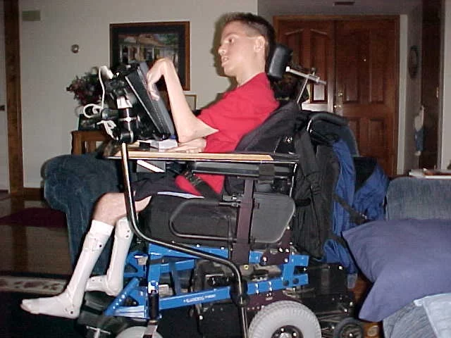 A wheelchair-bound man utilizing a laptop for home-based community services. A wheelchair-bound man utilizing a laptop for home-based community services.