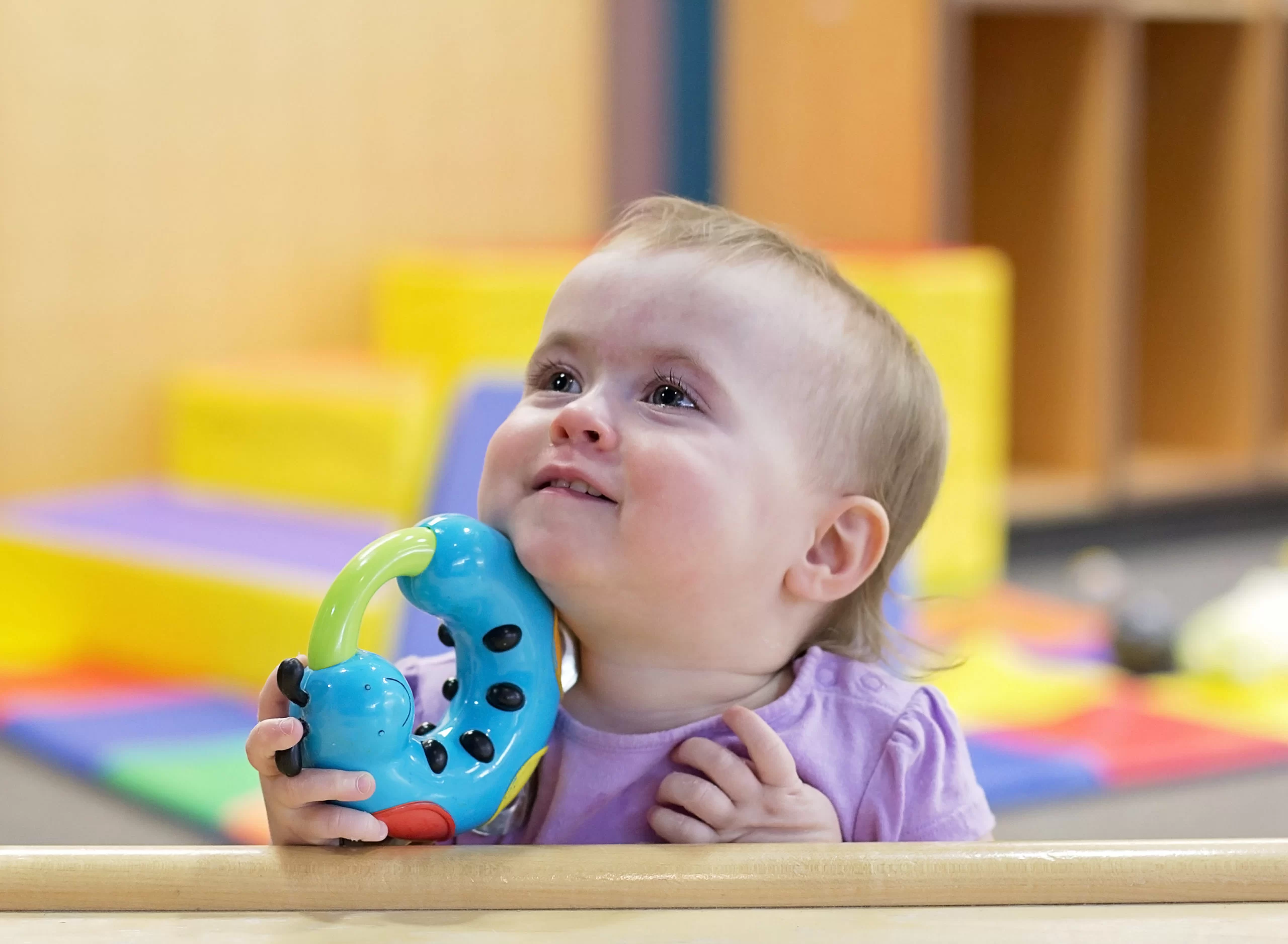 A baby with cerebral palsy playing with a toy in an early learning center. A baby with cerebral palsy playing with a toy in an early learning center.