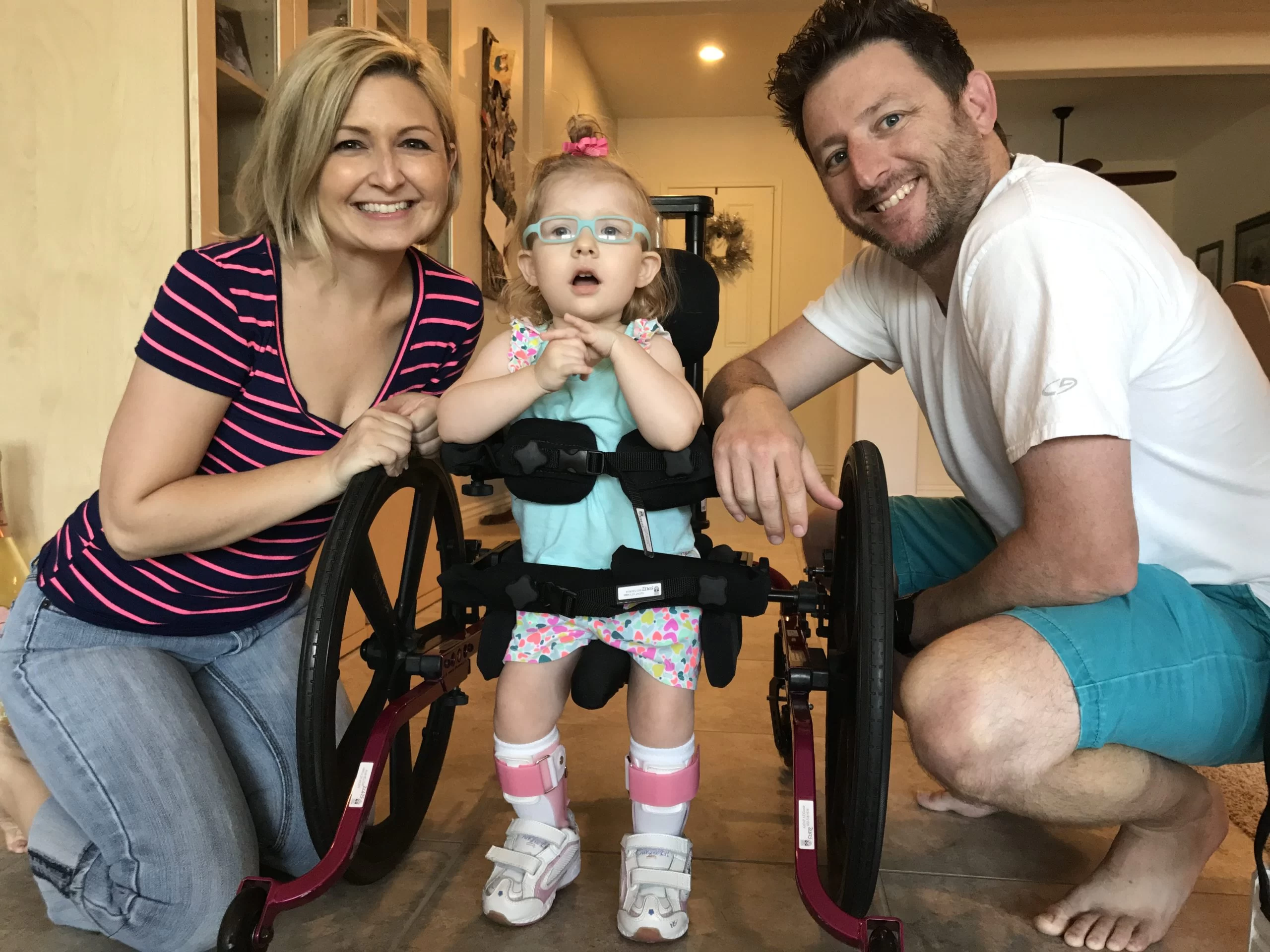 A little girl with cerebral palsy of Arizona poses for a photo with a man and woman, emphasizing the importance of pediatric therapy in home and community based services. A little girl with cerebral palsy of Arizona poses for a photo with a man and woman, emphasizing the importance of pediatric therapy in home and community based services.