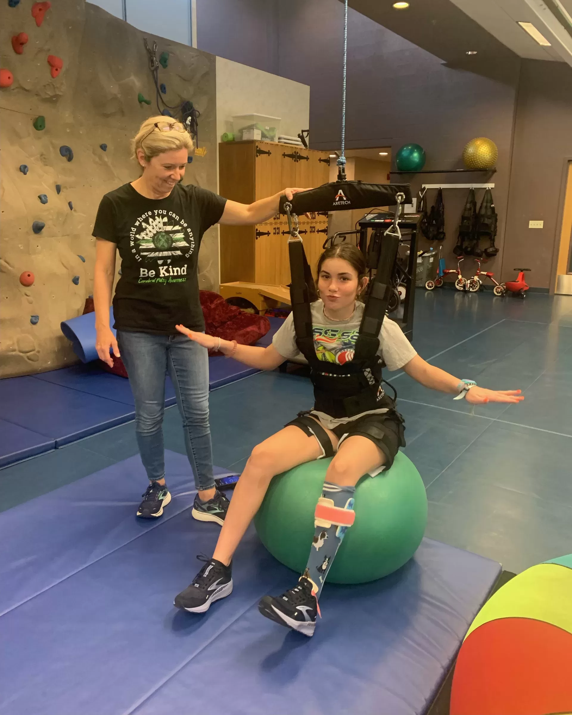A girl is using an exercise ball in a pediatric therapy session. Charlie Duffy in a pediatric therapy session.