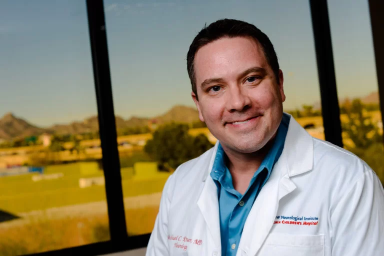 A man in a lab coat smiling during day treatment for adults at Cerebral Palsy of Arizona.