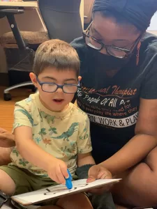 A woman at a pediatric therapy session is reading a book to a young boy with cerebral palsy of Arizona. A woman at a pediatric therapy session is reading a book to a young boy with cerebral palsy of Arizona.