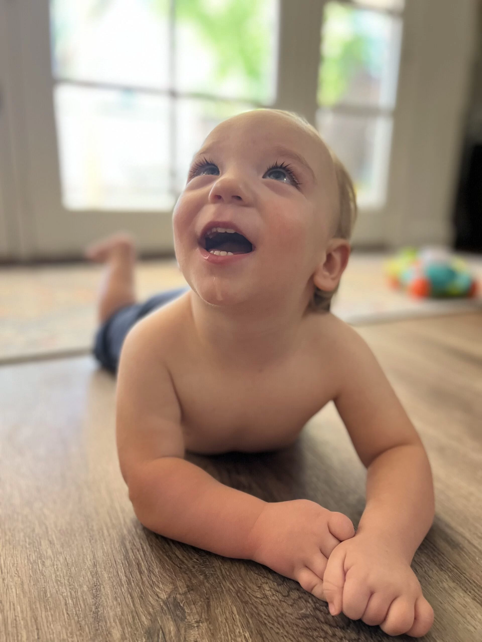 A baby is laying at home on the floor laughing. A baby is laying at home on the floor laughing.