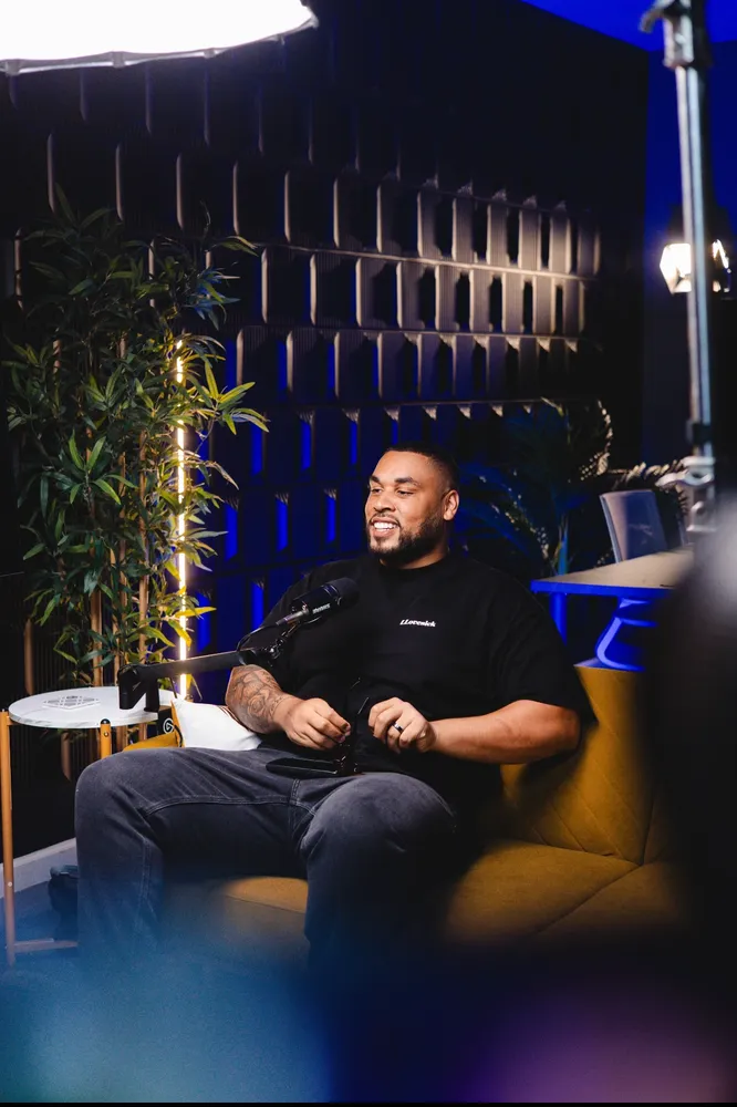 A UCP ambassador smiles while seated on a yellow couch in a modern setting with dark walls, a potted plant, and studio lighting. A UCP ambassador smiles while seated on a yellow couch in a modern setting with dark walls, a potted plant, and studio lighting.