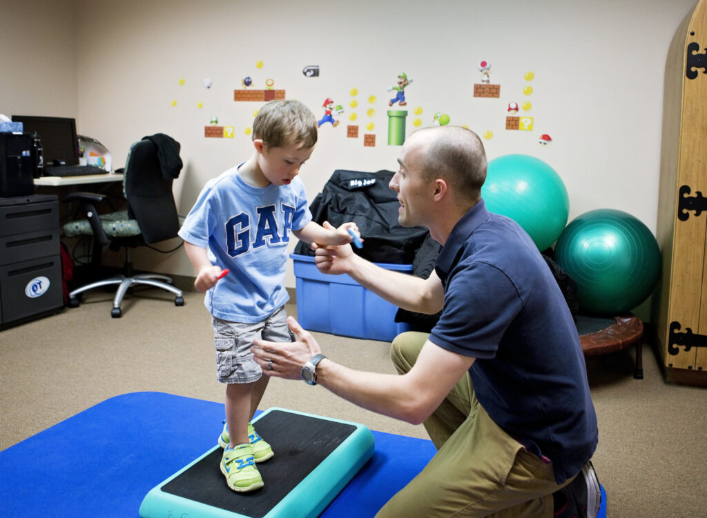 A young boy with cerebral palsy is being assisted by a pediatric therapist at the Early Learning Center in Arizona. A young boy with cerebral palsy is being assisted by a pediatric therapist at the Early Learning Center in Arizona.