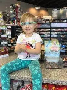 A little girl in glasses sitting at the counter of a pediatric therapy store. A little girl in glasses sitting at the counter of a pediatric therapy store.