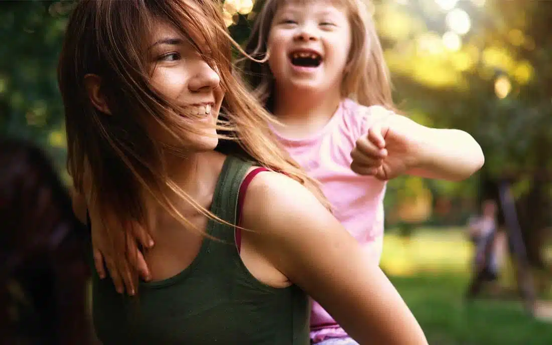 A woman and a little girl with cerebral palsy laughing in a park. A woman and a little girl with cerebral palsy laughing in a park.