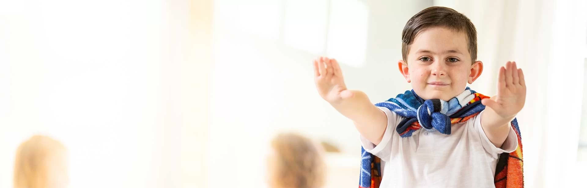A young boy receiving pediatric therapy, wearing a superhero cape. A young boy receiving pediatric therapy, wearing a superhero cape.