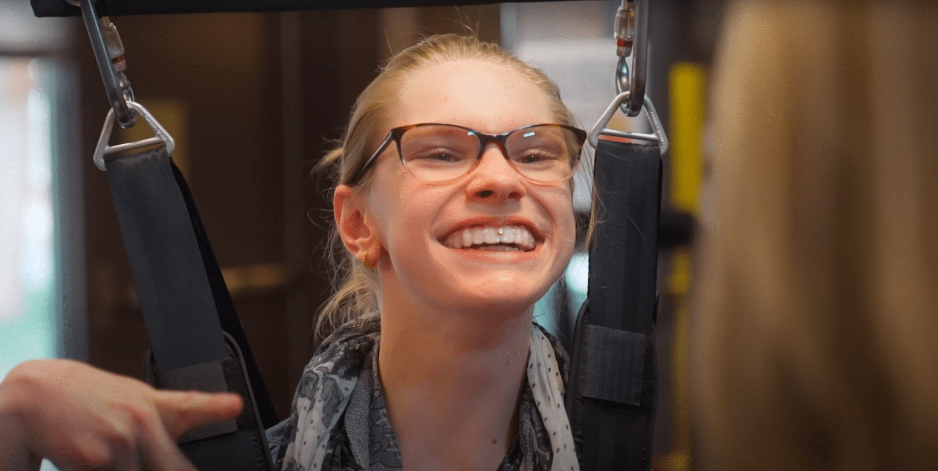 A girl wearing glasses is smiling on a zero G at a pediatric therapy center in Arizona.